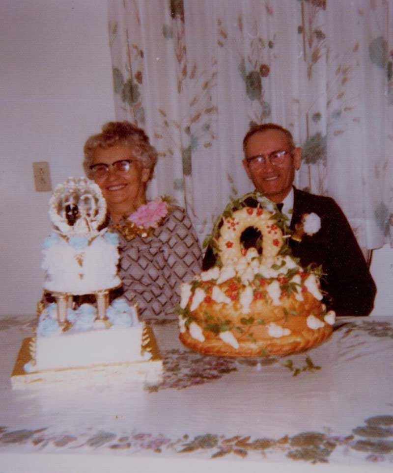 Un couple plus âgé s’assoit derrière deux gâteaux d’anniversaire.