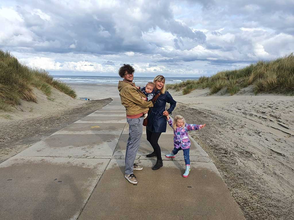 Un jeune couple avec de jeunes enfants se tient sur une promenade à la plage.