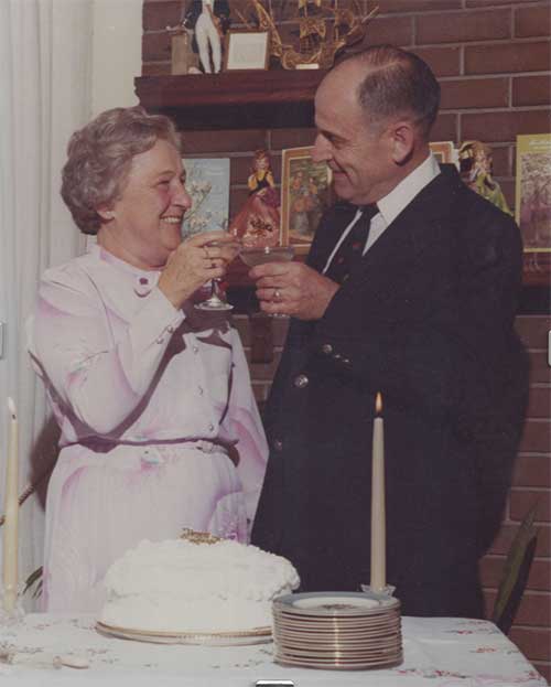 Un jeune couple tient des verres dans leurs mains et il y a un gâteau avec des bougies sur la table devant eux.