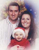 Portrait de Noël d’un jeune homme et d’une jeune femme, avec un bébé coiffé du père Noël rouge.