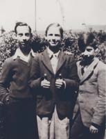 Trois jeunes garçons en veste de costume, un garçon du milieu avec le pouce levé.