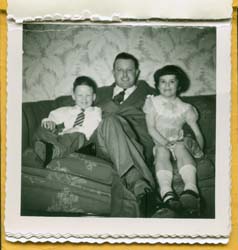 Père assis sur un divan entre un jeune garçon et une jeune fille.