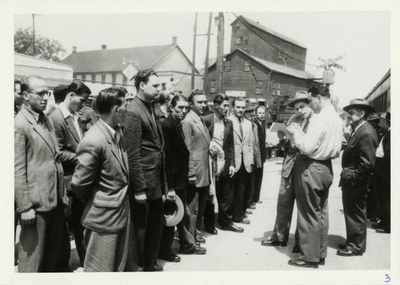 Deux hommes se tiennent debout face à une rangée d’hommes comme ils lisent d’un papier.