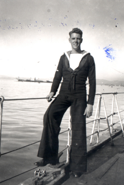Le jeune Jack en tenue de marin, debout contre la balustrade d’un bateau.