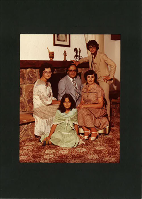 Une famille assise devant sa cheminée. Tout le monde porte des vêtements de soirée.