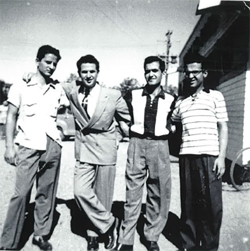 Quatre jeunes hommes côte à côte, bras dessus, bras dessous.