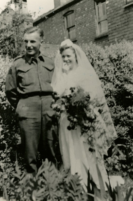 Belle jeune femme portant robe de mariée tenant des fleurs debout avec bel homme portant robe de l’armée.