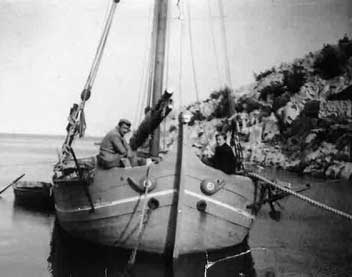 Vieille image en noir et blanc d’un navire avec deux hommes assis dedans.