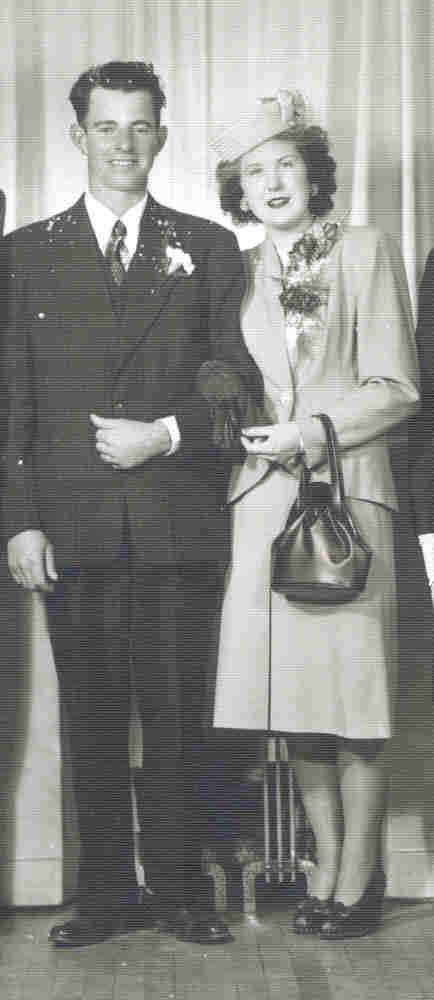 Un couple bien habillé se tient devant une toile de fond pour des photos.