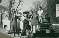Mère, père et enfants assis sur un vieux camion familial.