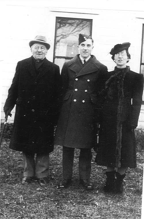Un jeune homme en uniforme militaire entre un homme et une femme.