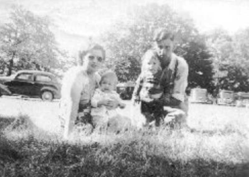 Jeune homme et femme assis sur l’herbe avec des enfants.