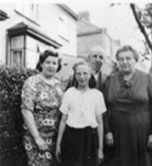 Famille debout devant la maison près des buissons pour une photo.