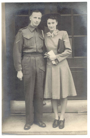 Homme en uniforme debout dans une entrée de porte et femme portant un chapeau noir.
