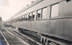 Plusieurs jeunes hommes, leur tête sortant des fenêtres d’un train qui passe.