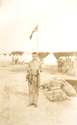 Jeune homme tenant du poisson, un drapeau et des tentes à l’arrière-plan.
