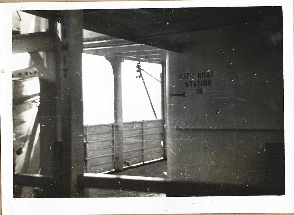 Photo en noir et blanc d’un pont de navire avec l’inscription Life Boat Station 10 sur le mur.