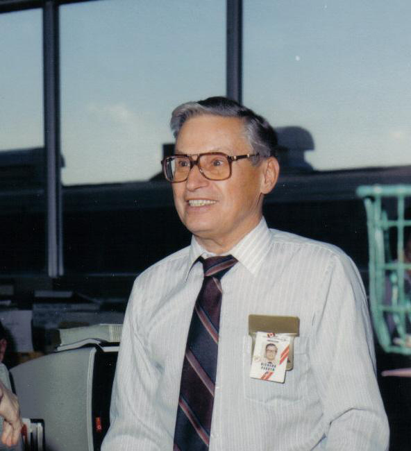 Homme d'âge moyen portant des lunettes et badge nominatif