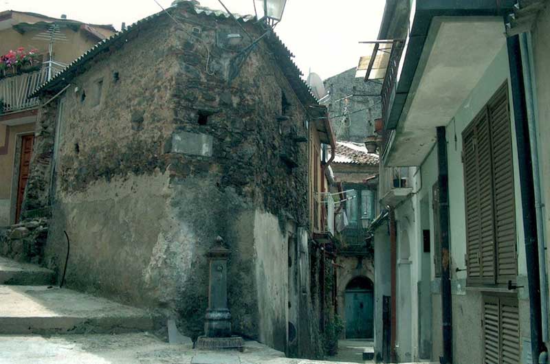Scène d’une rue pavée en Italie montrant une vieille fontaine d’eau.