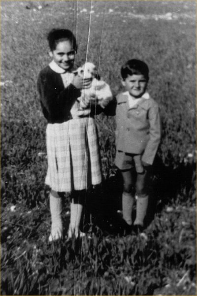 Luigi et sa sœur, enfants, debout dans un champ avec un petit chien.