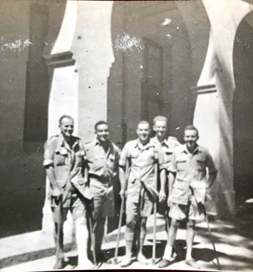 Photo en noir et blanc de cinq hommes tenant des béquilles.