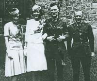 Jeunes mariés devant l’église avec un homme et une femme de chaque côté. 