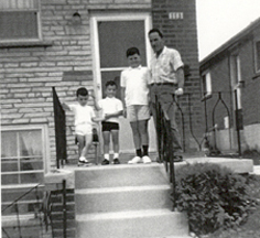 Giovanni et trois petits enfants sur les marches de ciment devant la maison.