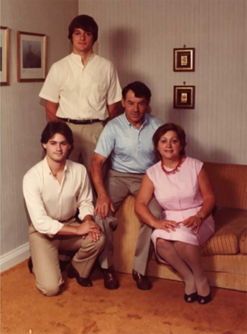 Une famille pose dans leur salon; la mère et le père sont sur le canapé et leurs deux fils sont à côté d’eux.