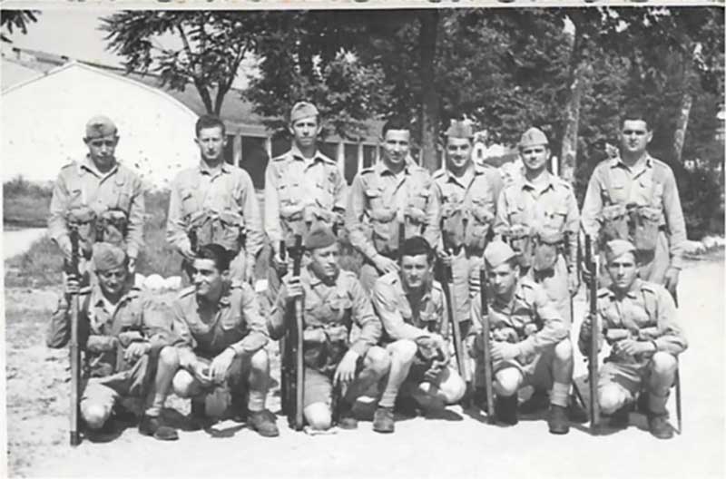 Groupe d’hommes habillés en uniforme militaire, ayant leur photo prise.