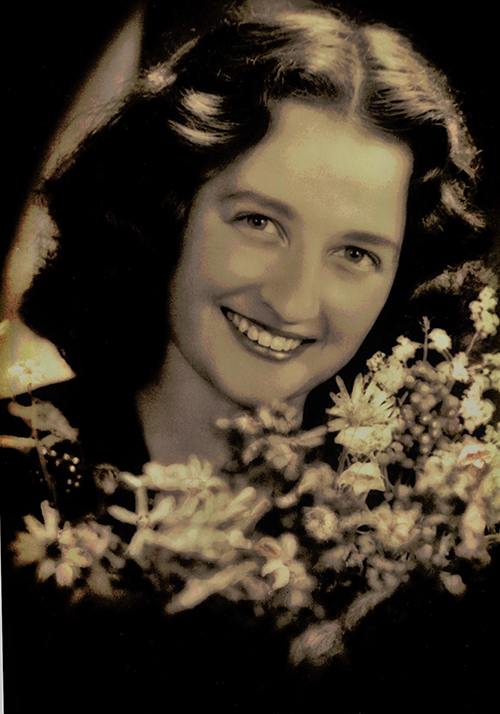 Jeune femme souriant pour la caméra alors qu’elle tient un bouquet de fleurs.