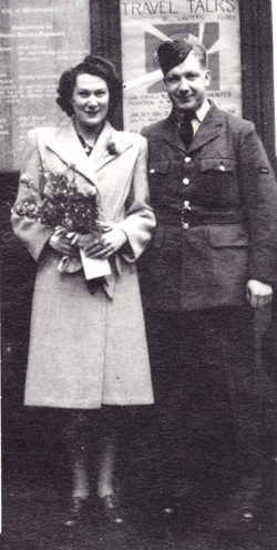 Homme en uniforme militaire avec un bras autour d’une femme tenant un bouquet.