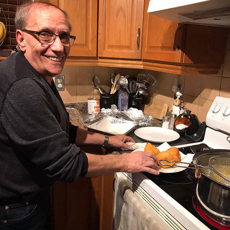 Un homme souriant fait cuire quelque chose sur la cuisinière.