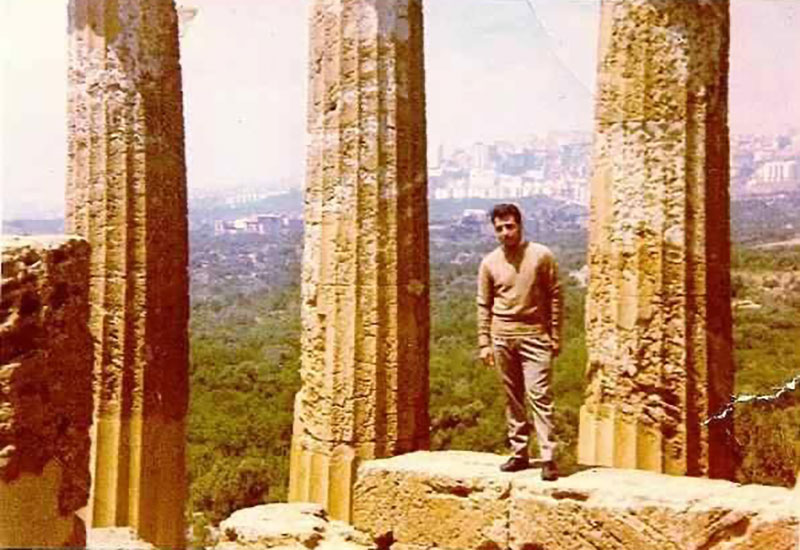 Un homme se tient entre deux colonnes sur un site de ruines antiques.
