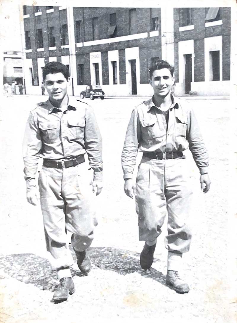 Deux hommes en uniforme militaire similaire marchent vers la caméra.