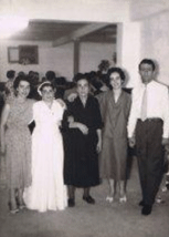 Quatre membres de la famille debout et une femme en robe de mariée.