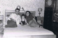 Homme et femme assis sur le lit avec un petit enfant entre eux.