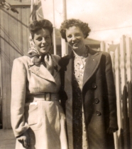 Jeune Norma debout avec une femme en veste blanche et foulard.