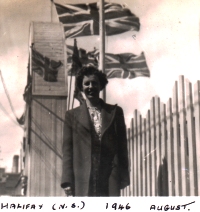 Jeune Norma, debout devant des bâtiments avec des drapeaux britanniques en arrière-plan.
