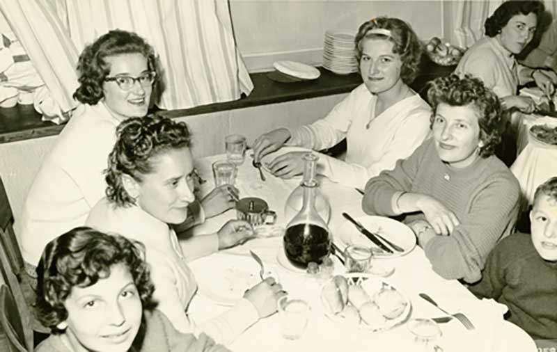 Quatre femmes et deux enfants sont assis autour d’une table.