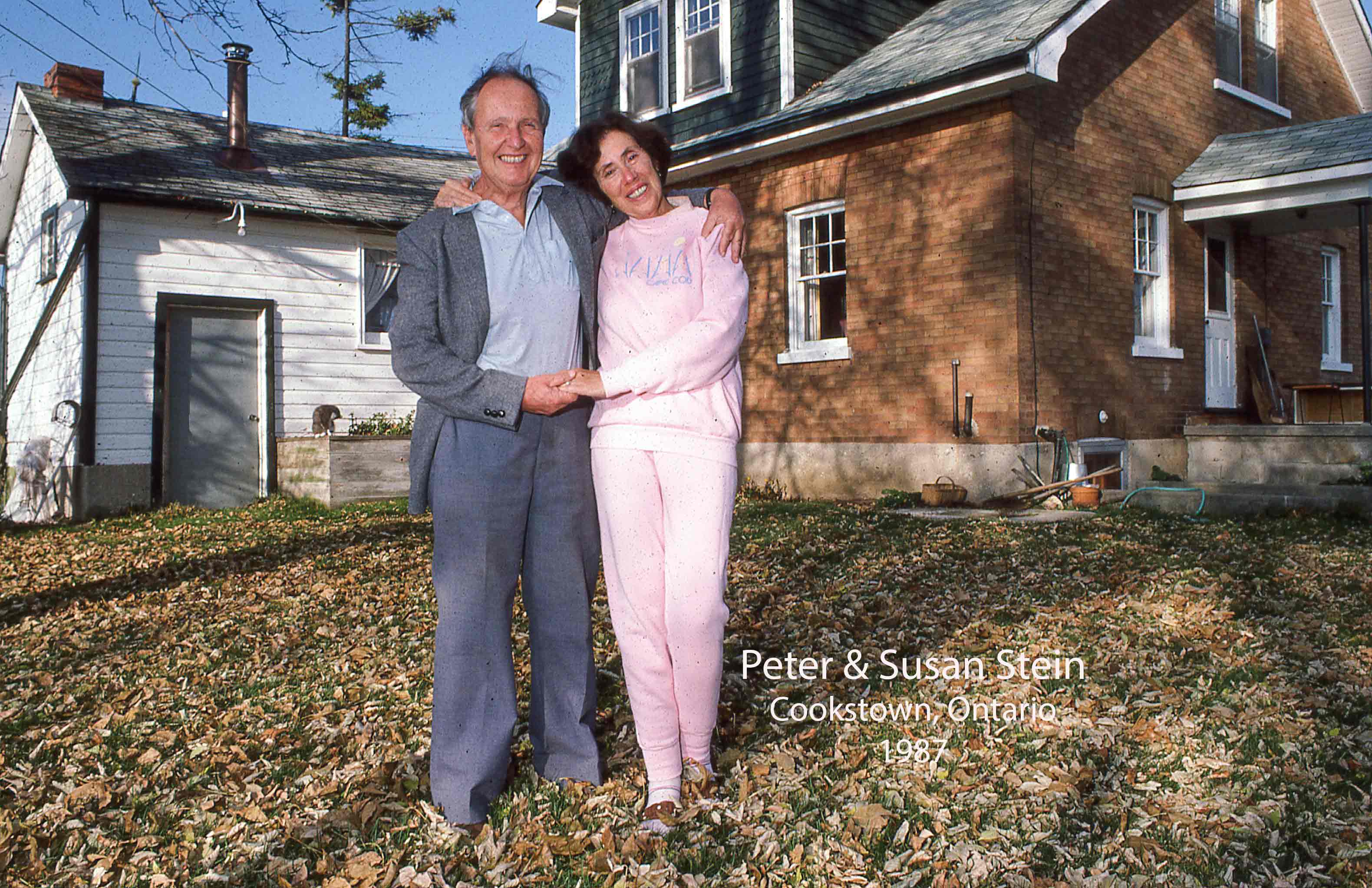 Un homme et une femme slovaques d’un certain âge à l’extérieur d’une maison, ils sont debout dans des feuilles d’automne et sourient à l’appareil photo.