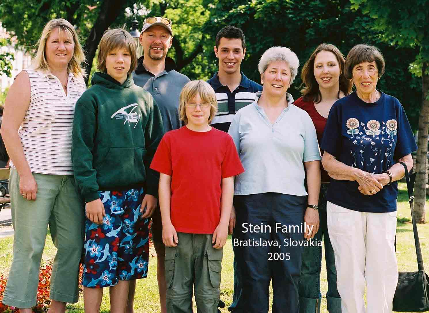 Les membres d’une famille slovaque, composée d’adultes et d’enfants, sont debout à l’extérieur et sourient à l’appareil photo.