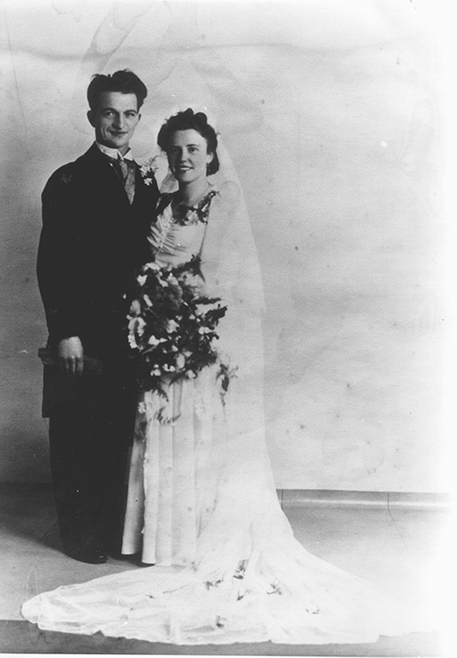 Couple nouvellement marié pose pour la photo tout en tenant des fleurs.