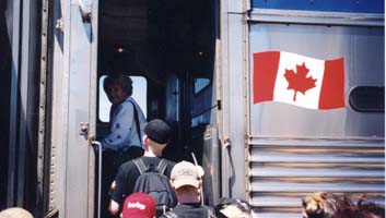 Des gens montent à bord d’un train avec le drapeau canadien sur le côté.