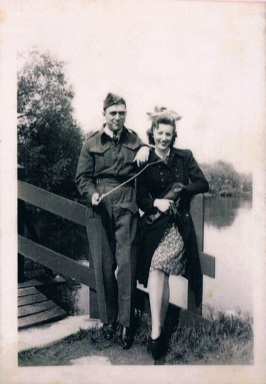 Un homme et une femme s’assoient sur la rambarde en bois d’un pont.