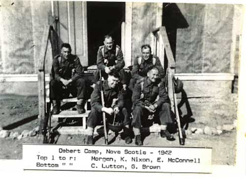 Cinq militaires s’assoient sur des marches de bois et sourient à la caméra.