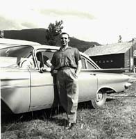 Jeune homme debout près d’une voiture ancienne.