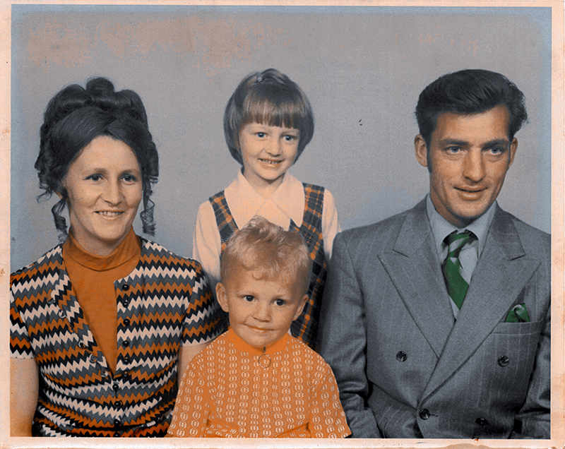 Portrait familial de la mère et du père et de deux enfants entre les deux, leurs vêtements rappellent les années 1970.