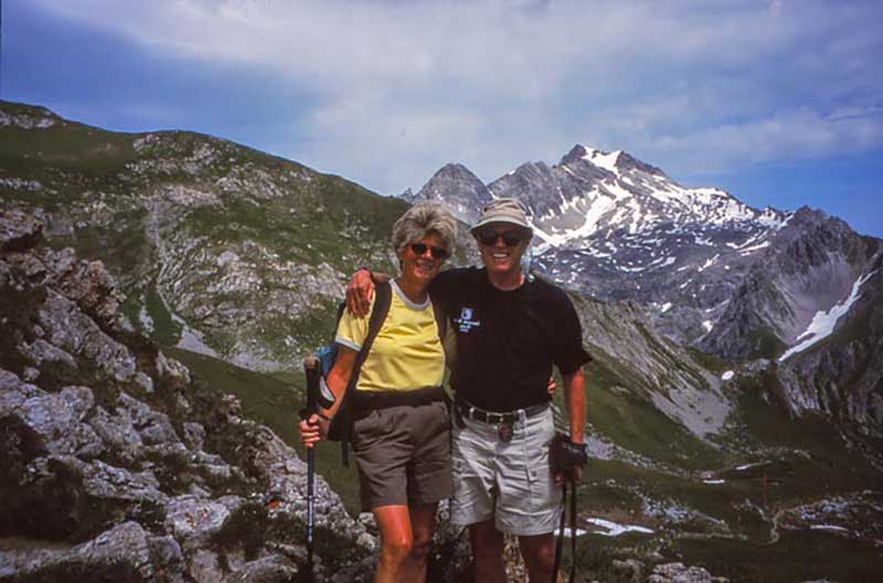 Un homme et une femme avec des engins de randonnée se tiennent devant un fond vallonné.