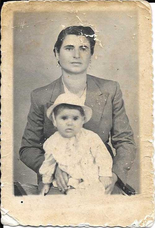 Vieille photo craquelée d’une femme avec un bébé sur ses genoux.
