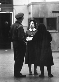 Sœur Liota en tenue de religieuse traditionnelle, parlant à une autre femme et à un homme. 